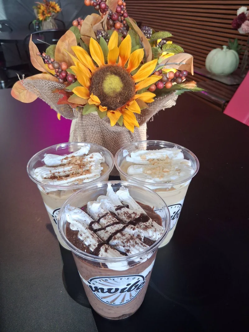 Three topped Pie Day cups in branded InVibe cups beside sunflowers