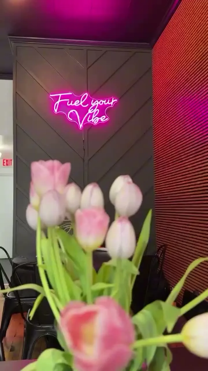 Flowers and the pink Fuel Your Vibe neon sign inside InVibe