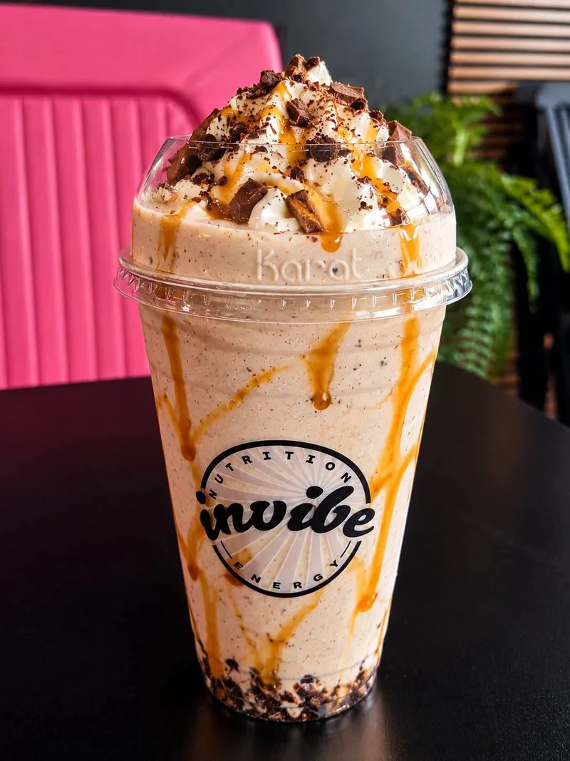 A topped shake in an InVibe cup beside the pink seating