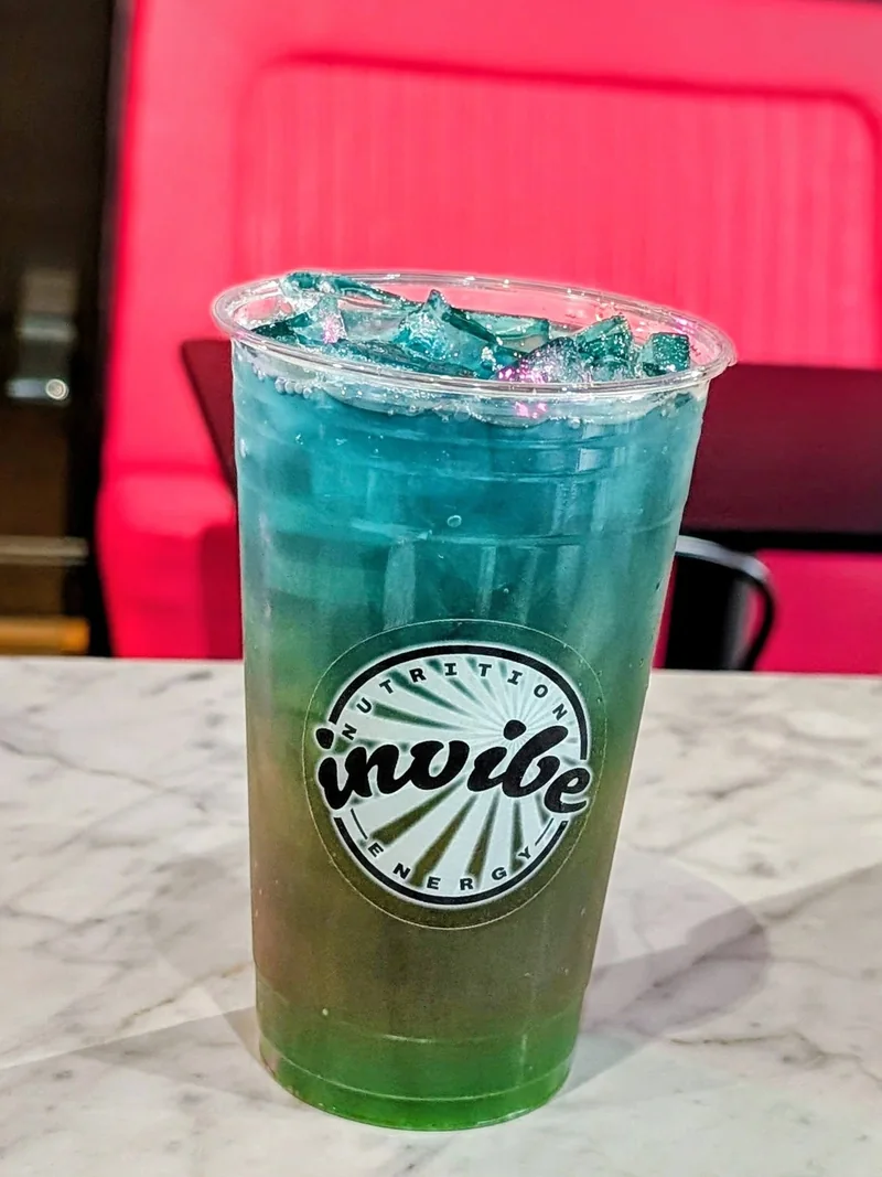 An aqua and green InVibe tea on a marble table beside the pink seating